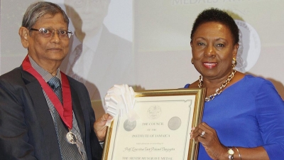 The Minister of Culture, Gender, Entertainment and Sport, the Honourable Olivia Grange, CD, MP (right) makes presentation to Professor Tara Dasgupta, CD