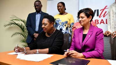 The Ministry of Culture, Gender, Entertainment and Sport, the Honourable Olivia Grange (left) signs the Memorandum of Understanding with the UWI Open Campus for sexual harassment training in workplaces. The Pro-Vice Chancellor and Principal of the UWI Open Campus, Dr Luz Longsworth (seated right) as well as the Permanent Secretary in the Ministry, Denzil Thorpe (standing left) and the Senior Director of the Bureau of Gender Affairs, Sharon Robinson (standing 2nd left) look on.