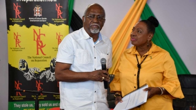 The Minister of the Culture, Gender, Entertainment and Sport, the Honourable Olivia Grange, accepts a copy of ‘Report on Reparations for Transatlantic Chattel Slavery in the Americas and the Caribbean’ from Judge Patrick Robinson of the International Court of Justice. The historic report quantifies reparations for transatlantic chattel slavery.