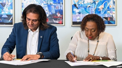 The Minister of Culture, Gender, Entertainment and Sport, the Honourable Olivia Grange (right), signs the agreement for the development of an app to enable people facing gender-based violence to call for help. The app is being developed by Amber Innovations. The company's CEO, Ambassador Dushyant Savadia (left) also signs the agreement at the Ministry's headquarters on 14 August 2026.
