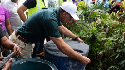 Prime Minister, the Most Honourable Andrew Holness, applies net to water drum in Grants Pen, St Andrew.