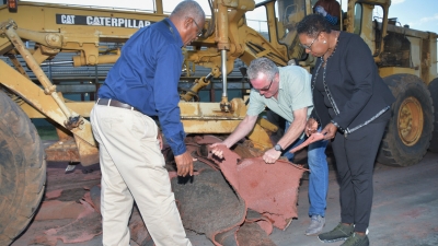 Minister of Culture, Gender, Entertainment and Sport, the Honourable Olivia Grange (right) examines a piece of the old turf at Stadium East as work got underway to remove the old track which will be replaced by a new Regupol track. The track is scheduled to be ready for use before the end of February. Explaining to the Minister the process for changing the track is Peter Breuer, Director Export, BSW, Germany (centre), while Major Desmon Brown, General Manger, Independence Park Limited looks on.